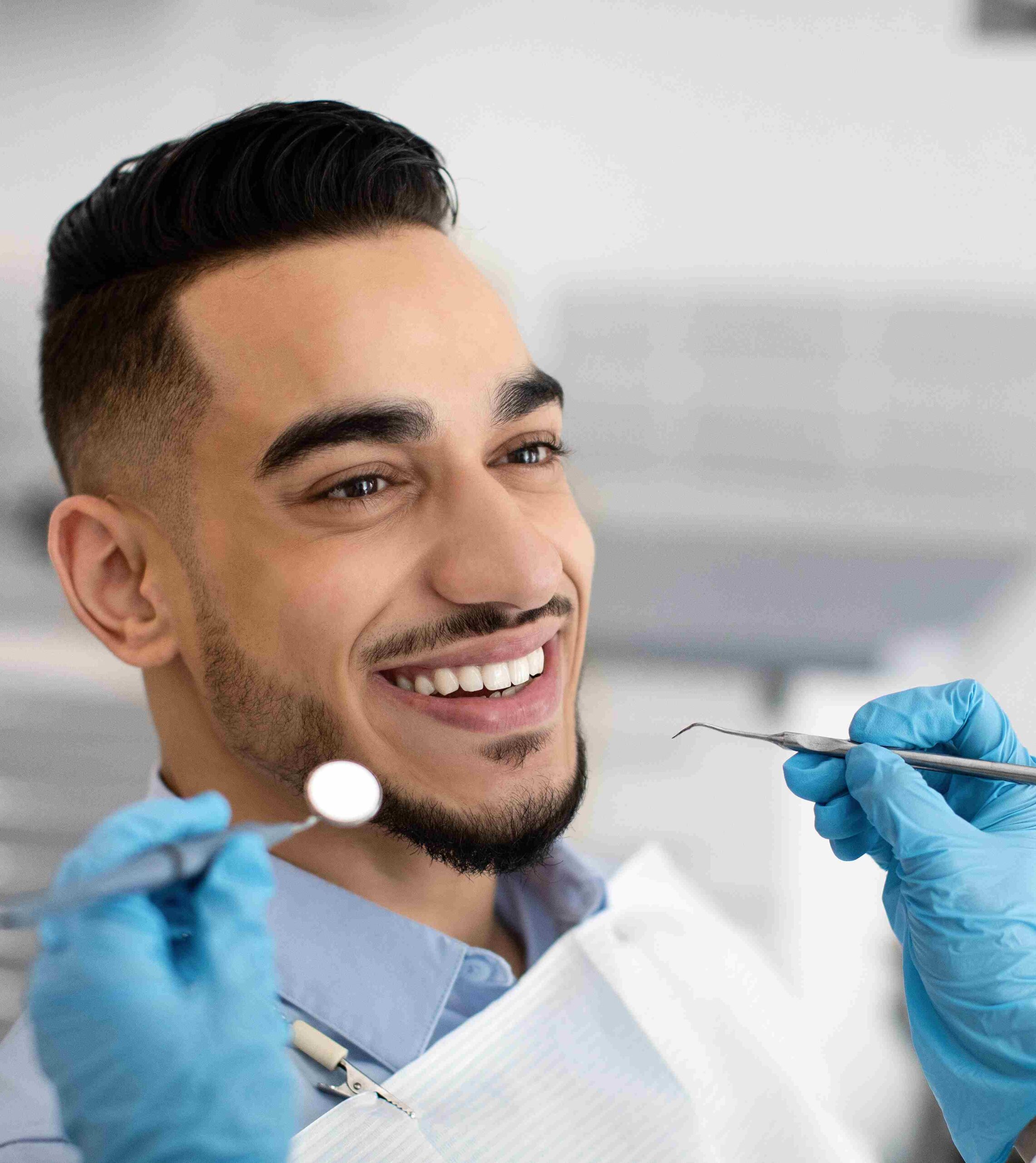 closeup of happy middle eastern male patient getting dental treatment in modern clinic