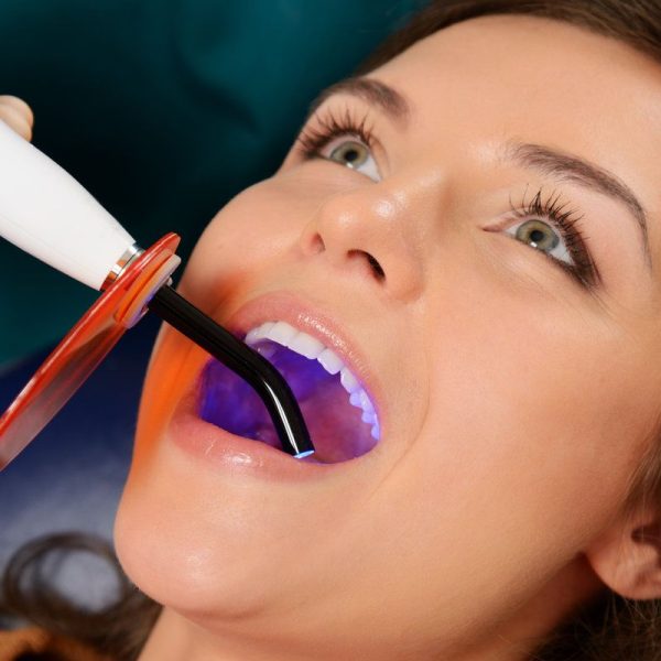 Woman receiving dental treatment with light